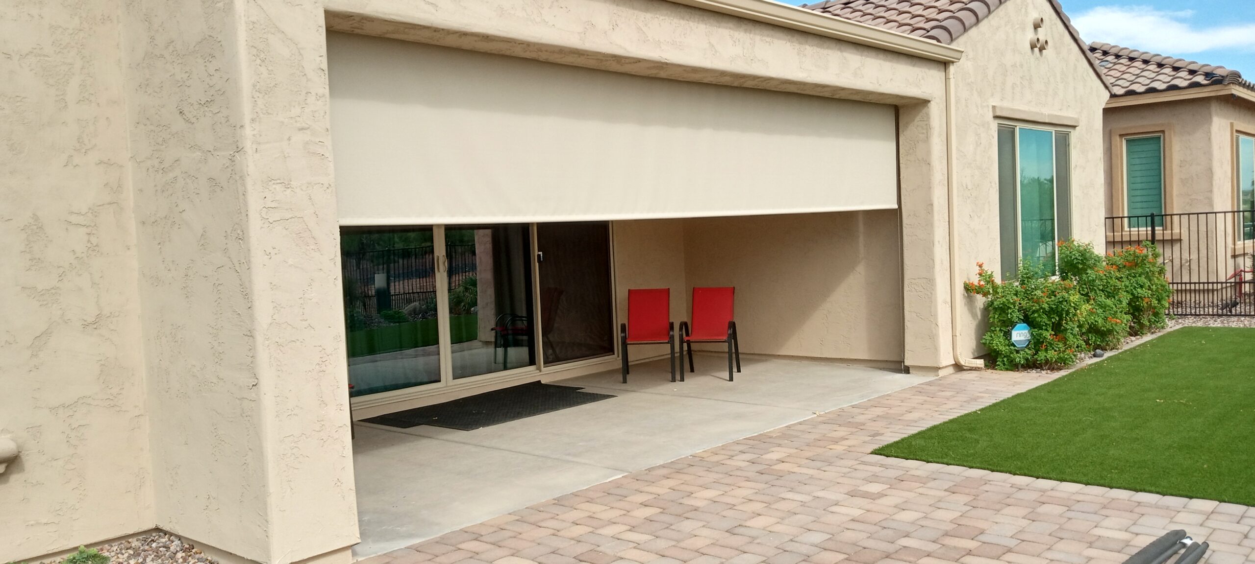 Retractable patio shade rolled down over a home garage-style opening with outdoor seating underneath