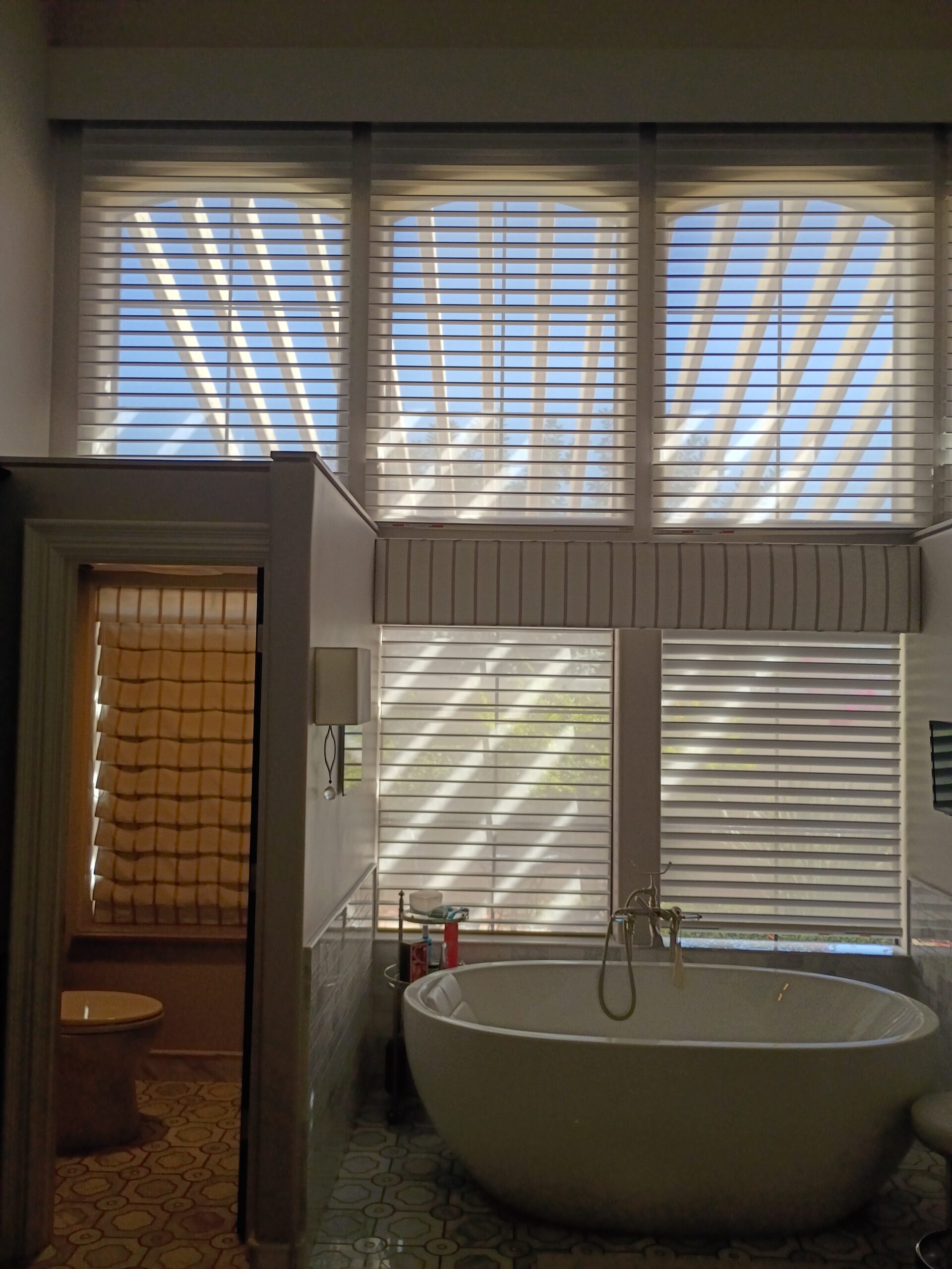 Horizontal wood blinds installed on tall bathroom windows