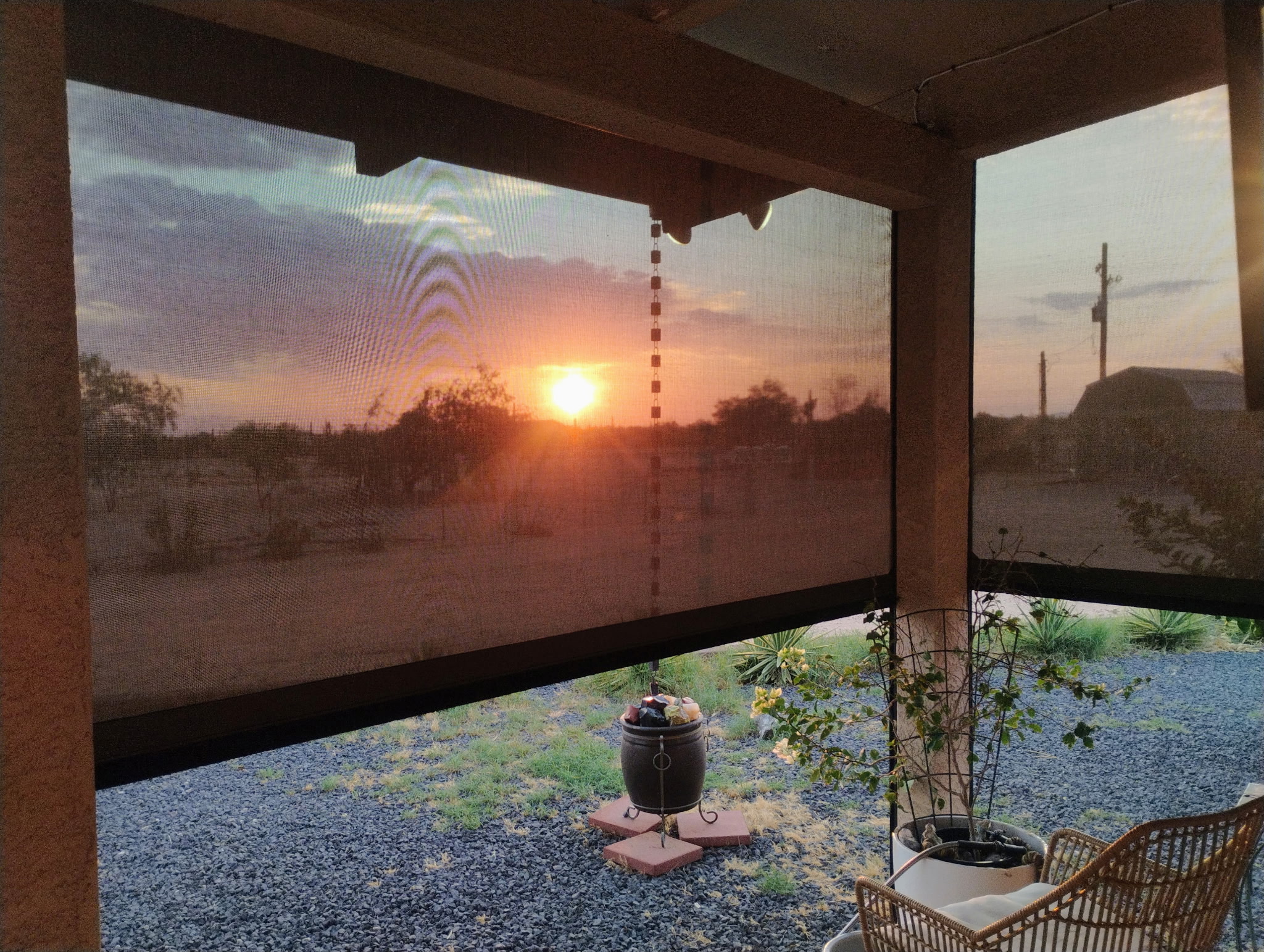 Patio shade lowered along the edge of a covered patio, filtering sunlight over outdoor seating