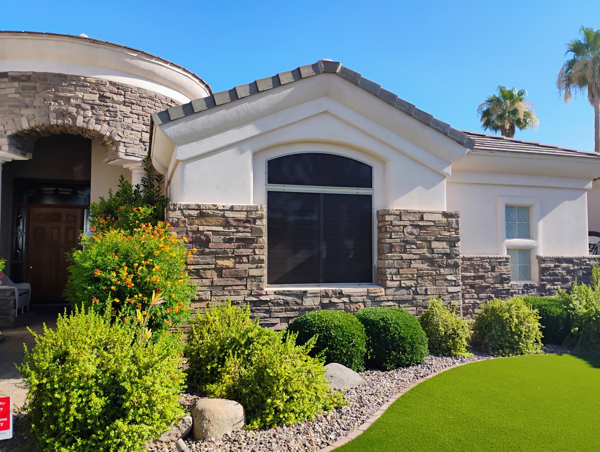 Stone and stucco Mesa home with an arched sun screen over a large window