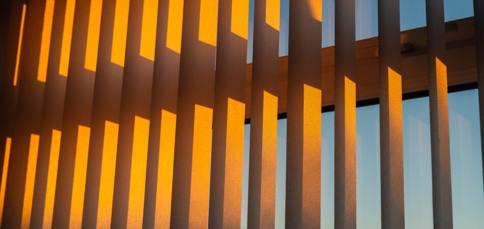 Hanging,white,textured,vertical,window,slats,reflecting,the,gold,of