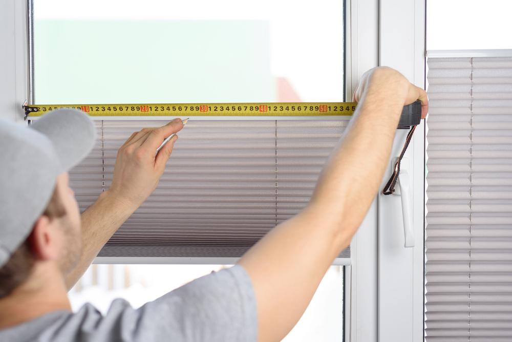 Technician measuring a window for custom blinds installation